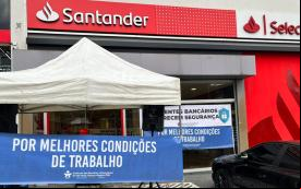 Imagem mostra fachada de uma agência do Santander. Em frente a ela está estendida uma faixa onde se lê "por melhores condições de trabalho"