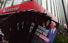 Foto mostra o folder sobre o novo canal de denúncias, onde se lê ""Trabalho dogno não tem assédio", diante da fachada da Torre Santander