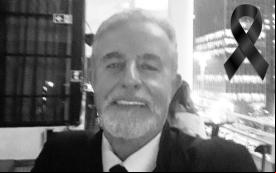 Imagem de Carlos Miguel Gonçalves, em preto e branco, com um laço preto de luto no canto superior direito. Carlos Miguel era um homem de 72 anos, branco, de cabelos e barba grisalha. Na foto ele aparece sorrindo