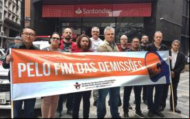 Imagem mostra dirigentes do Sindicato dos Bancários de São Paulo em frente ao Quarteirão de Investimentos, portando uma faixa onde se lê "pelo fim das demissões"