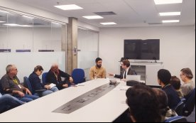 Imagem da reunião entre o Sindicat e a Ditec. A foto mostra uma sala onde estão reunidos, em uma mesa comprida e branca representantes do sindicato e funcionários